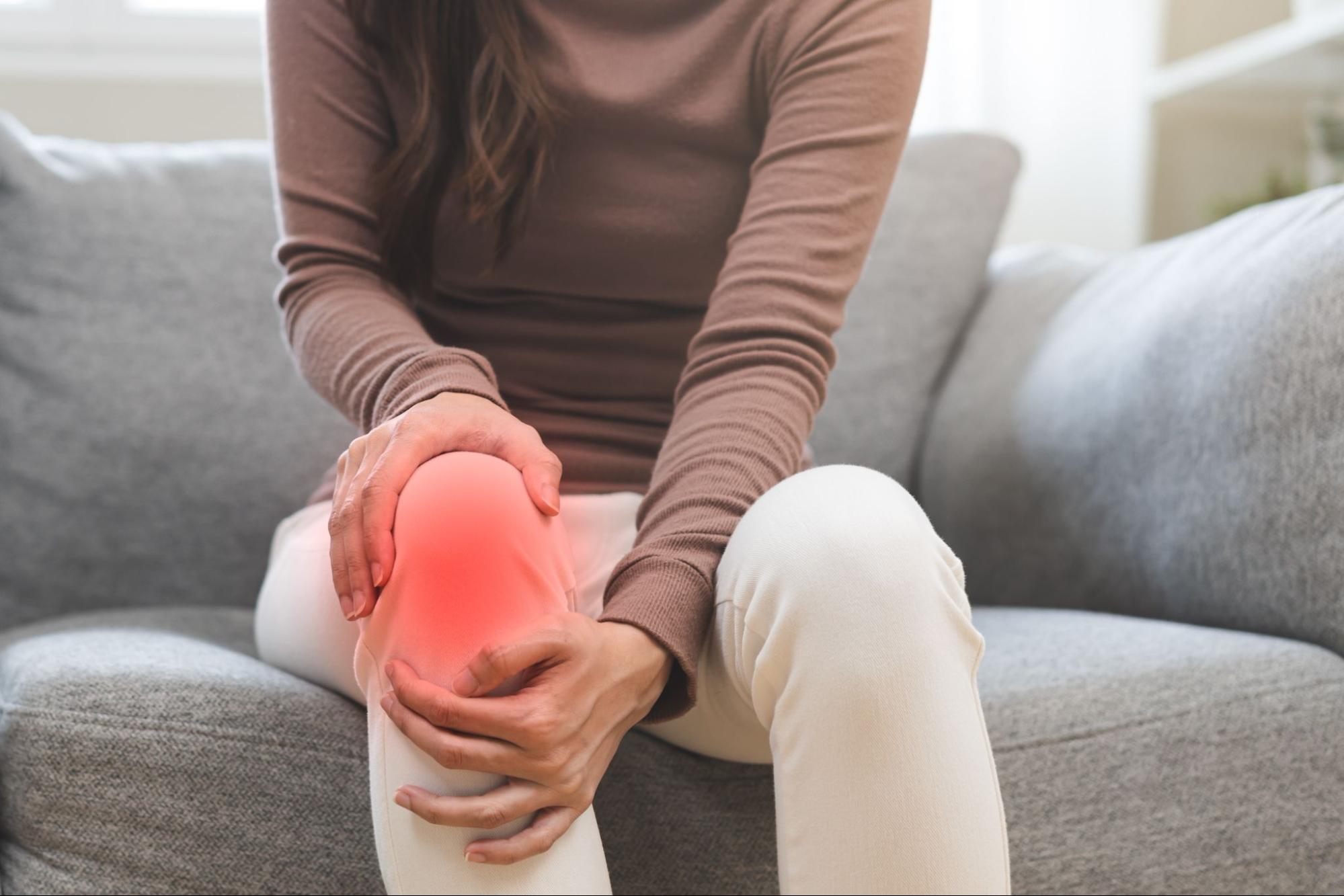 A person holds their knee due to chronic pain symptoms.