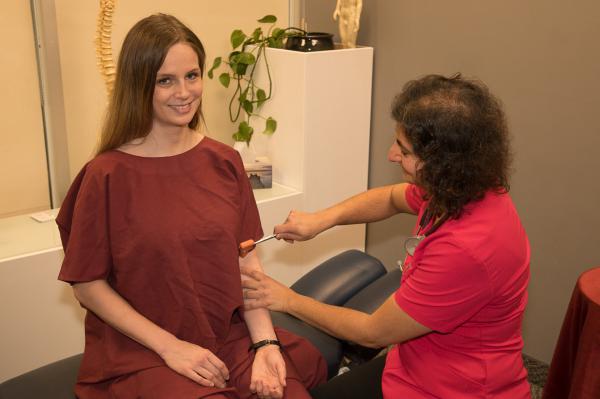 Dr. Alma performs a reflex test with a patient.