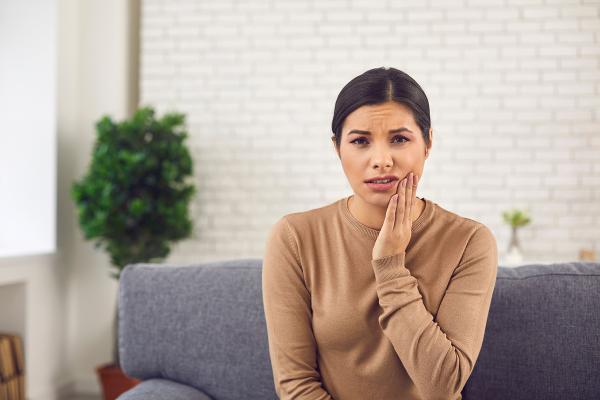 A woman holding her jaw in pain.