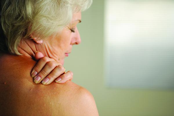 A woman rubbing her shoulder in pain.