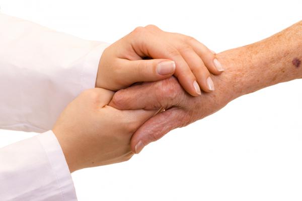 A younger person's hands holding an older person's hand.