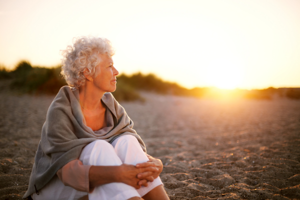  A woman sitting on the beach at sunrise.